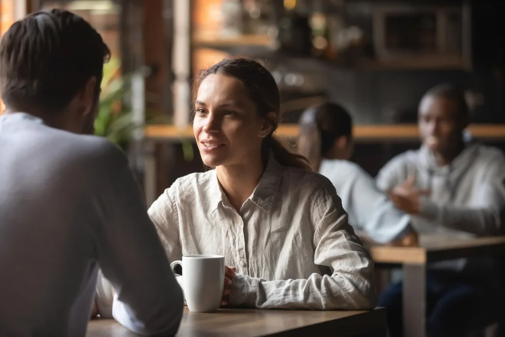 Beautiful millennial woman looks attentively at his partner while he talks about their future
