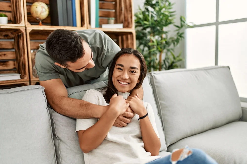 Young couple sitting on the sofa hugging at home