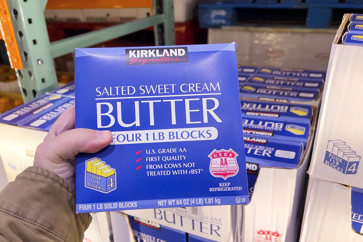 Sacramento, California, USA December 14th 2023 Shoppers hands holding a package of Kirkland brand salted sweet cream butter blocks at Costco