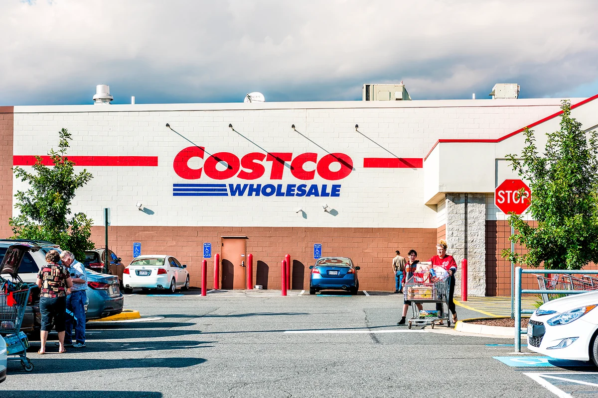 Fairfax, USA - September 8, 2017: People with shopping carts filled with groceries walking out of Costco store in Virginia in parking car lot