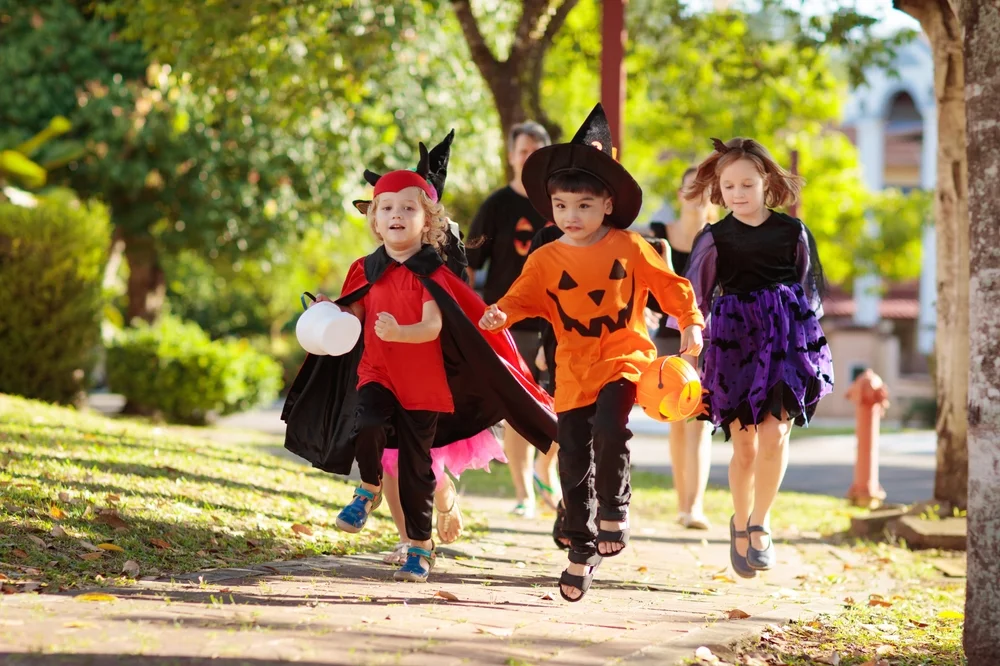 Diverse group of children dressed in Halloween Costumes playing a scavenger hunt