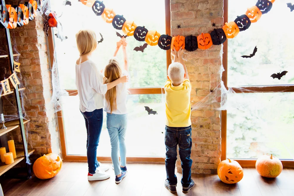 Mother and two kids setting cute decor for a Halloween party