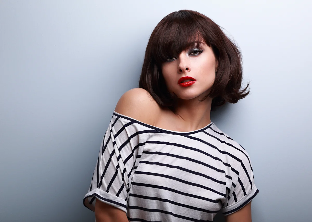 Sexy makeup short hair woman in casual clothes posing on blue background with empty copy space