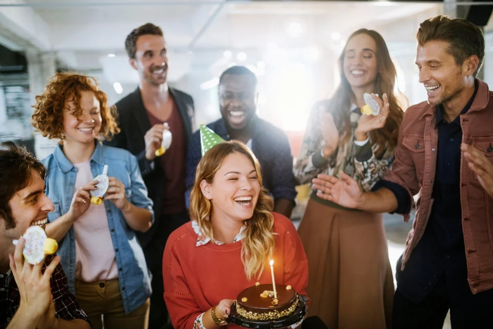 Group of diverse friends celebrating a birthday with cake