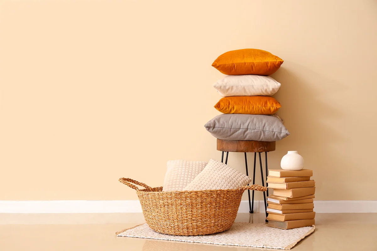 Stack of soft pillows on chair and books in stylish room