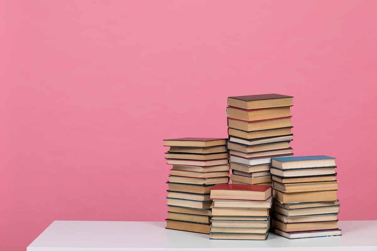 stack or pile of books on wooden table, one of them open with copy space
