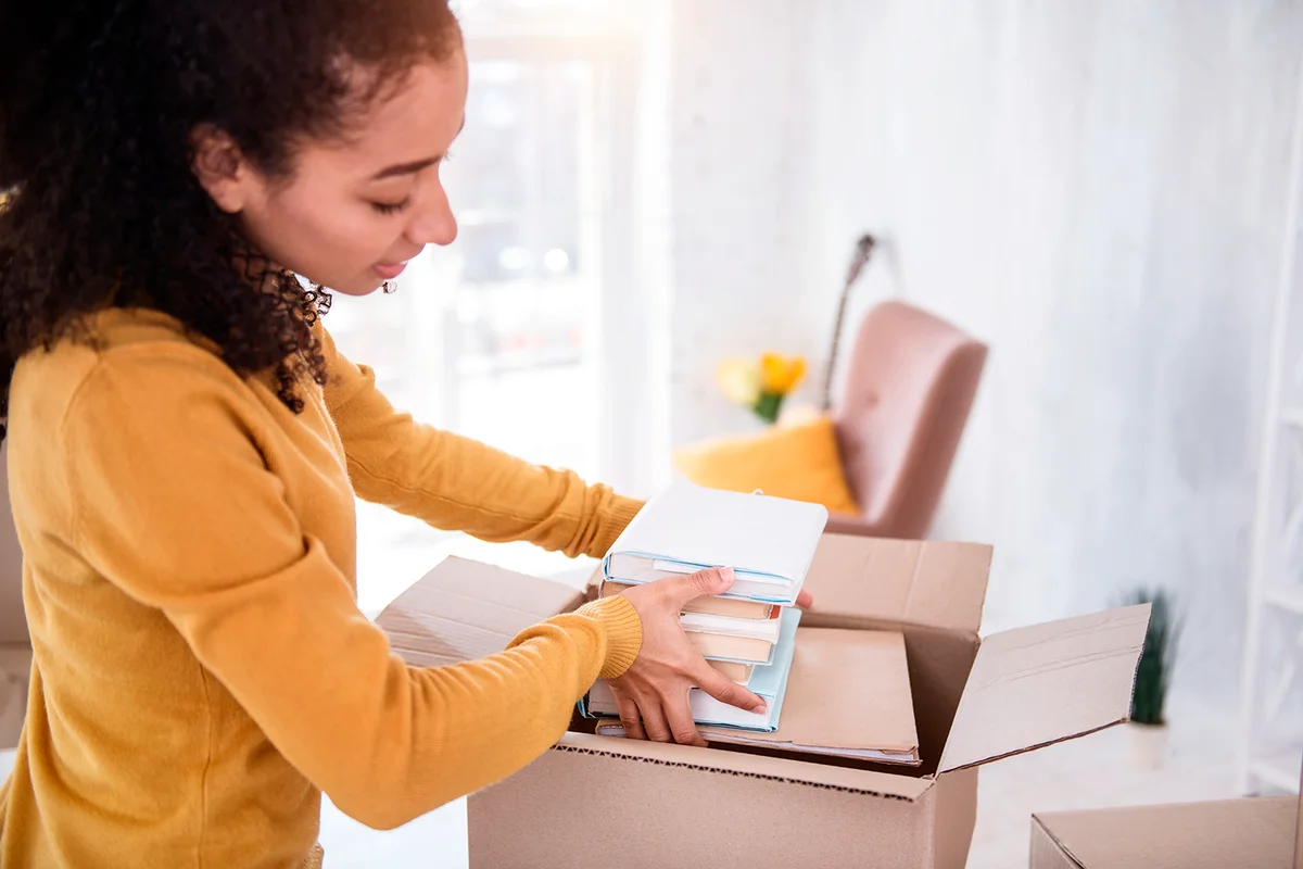 Girl fitting a pile of books into the box