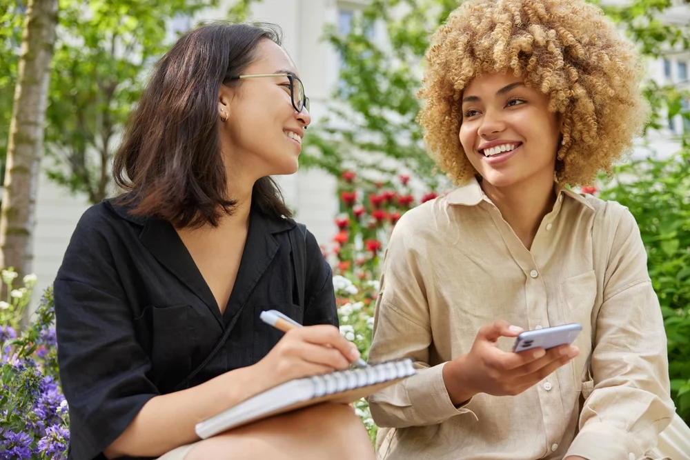 Positive woman talks with another woman confidently outdoors