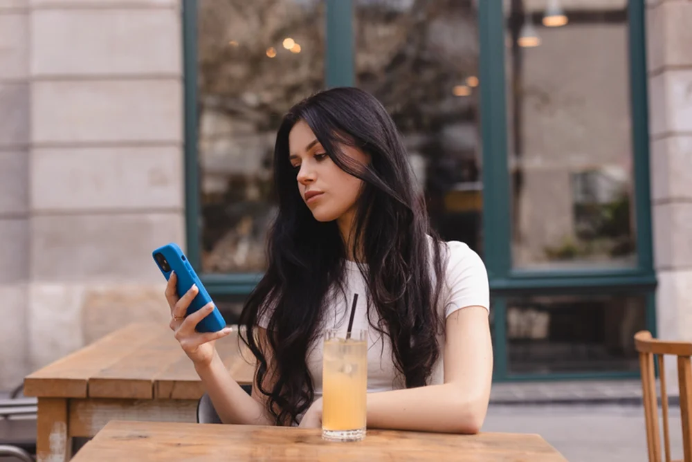 Focused Libra-Scorpio Cusp woman frowning at her phone outside