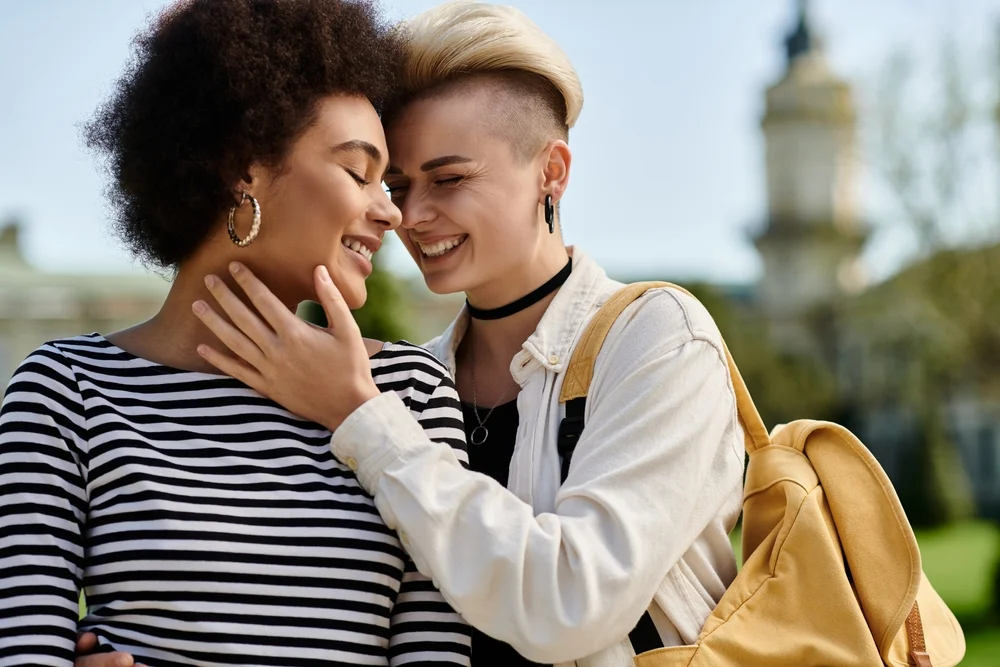 A couple of young women embrace each other warmly in a park