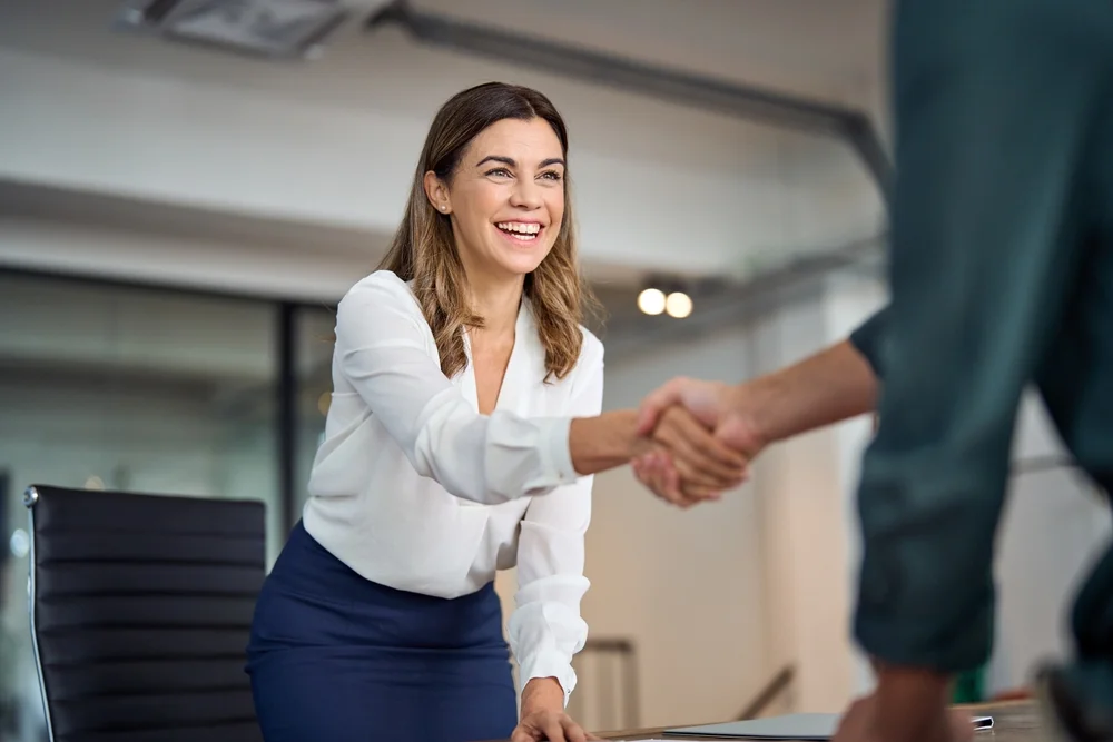 Succesful business woman handshaking client at her office