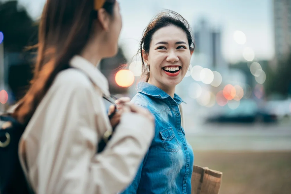 Two Asian women chat and look at each other in the city