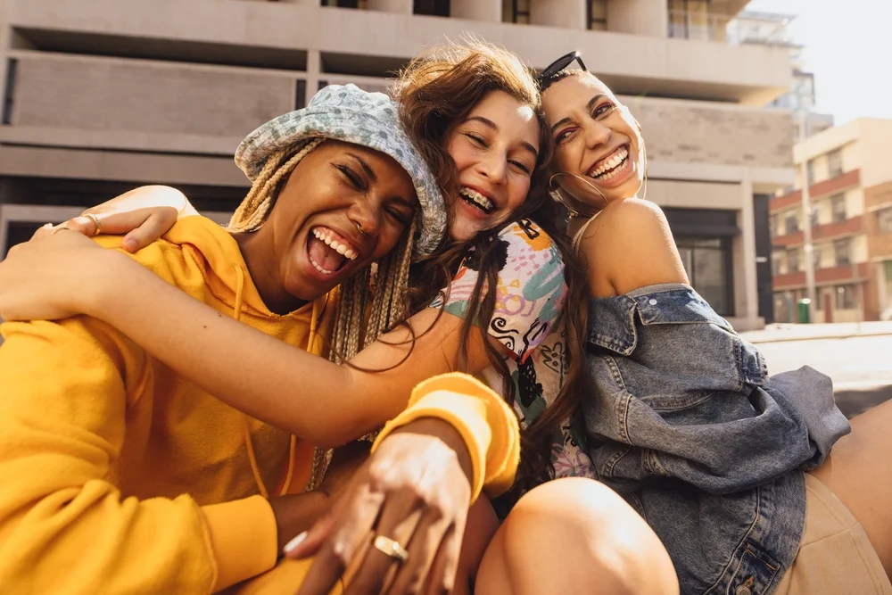 Three female friends laughing together on a city rooftop