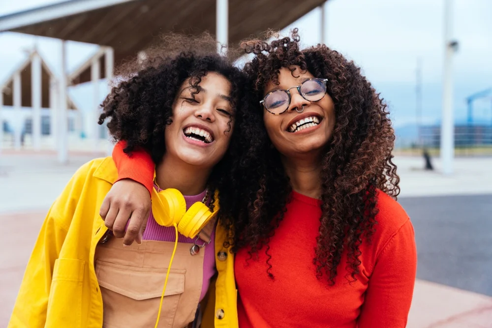 Happy young woman embracing her friend and laughing outdoors