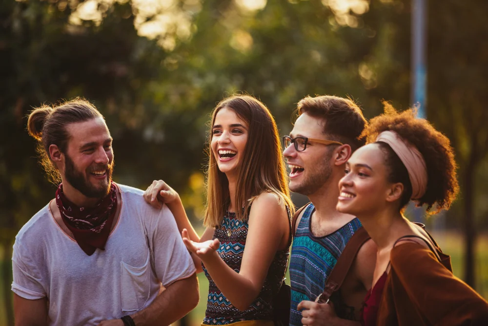 Middle shot of four joyful young friends having fun in a beautiful park