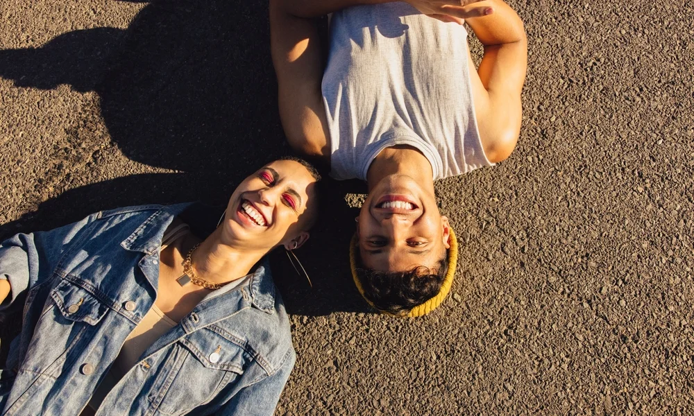 High-angle view of two happy youngsters laughing while lying outdoors under the sun