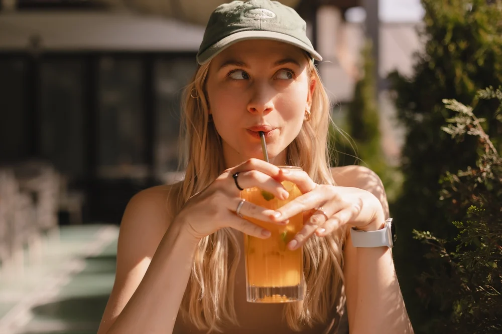 Close-up portrait of a caucasian Virgo woman making a funny face while having a fresh drink.