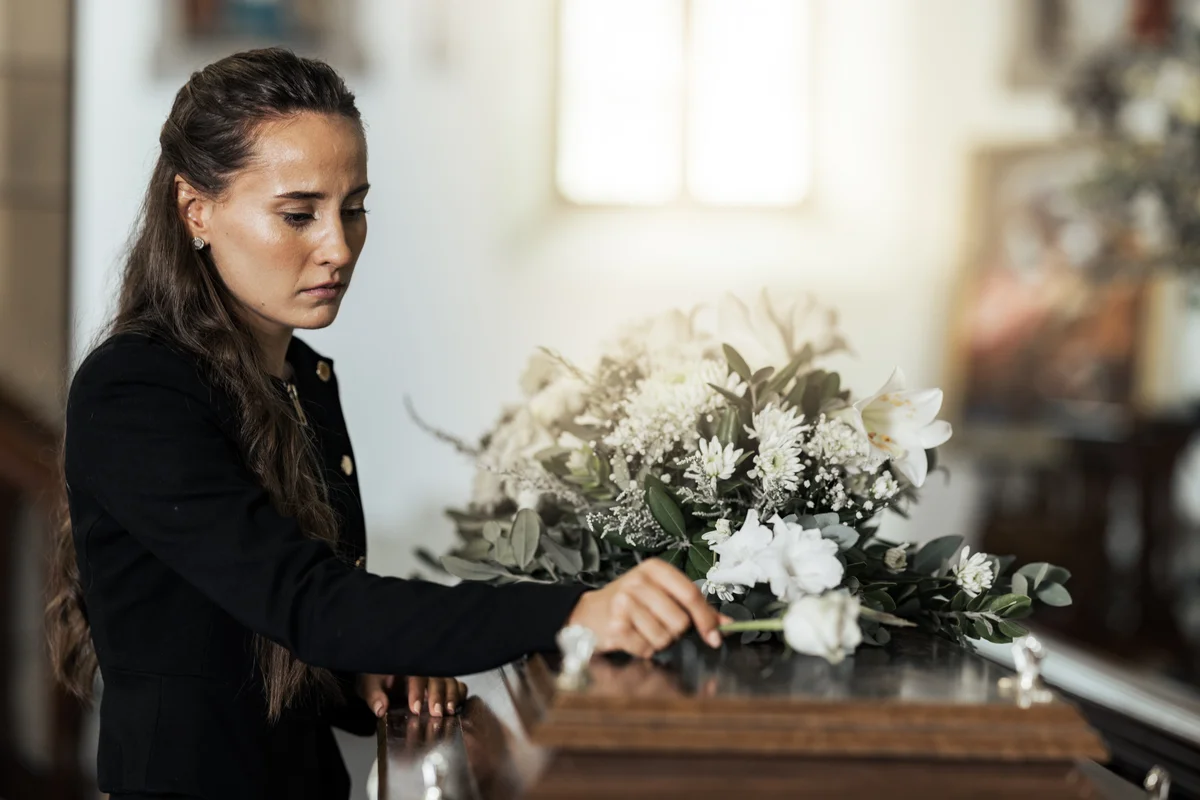 sad woman with flower on coffin after loss of a loved one