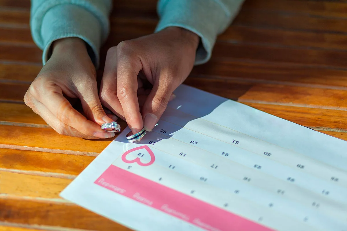 two hands holding wedding rings on a calendar