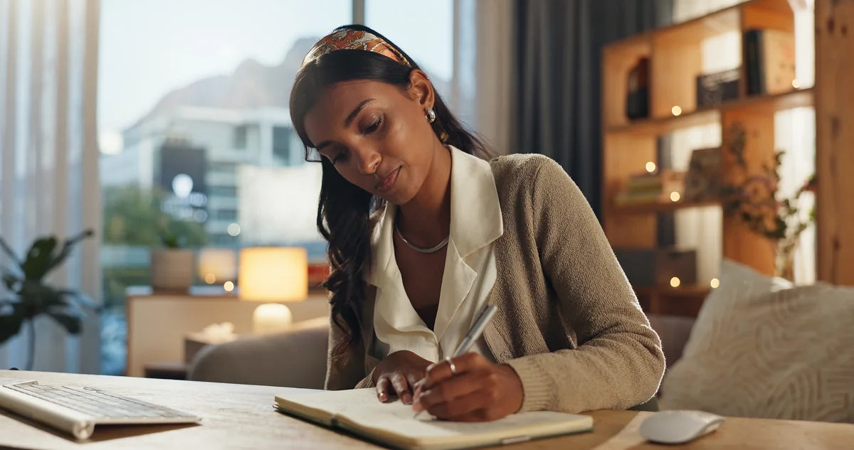 woman at her desk writing in a notebook