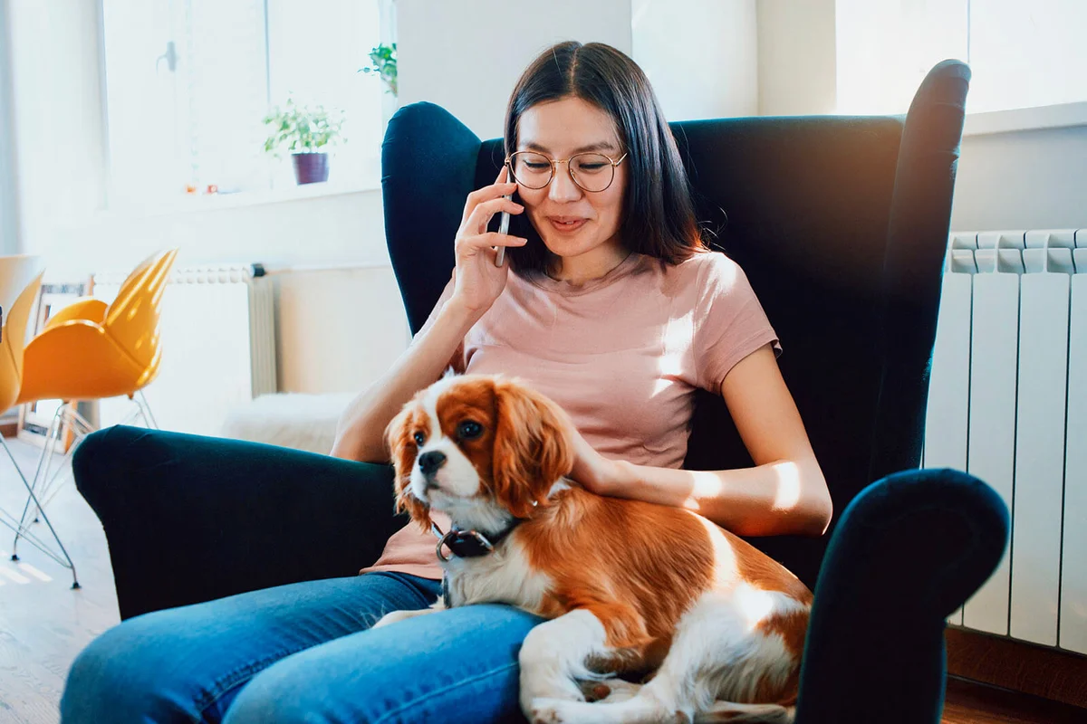 woman relaxing at home and talking on the phone in the company of her puppy