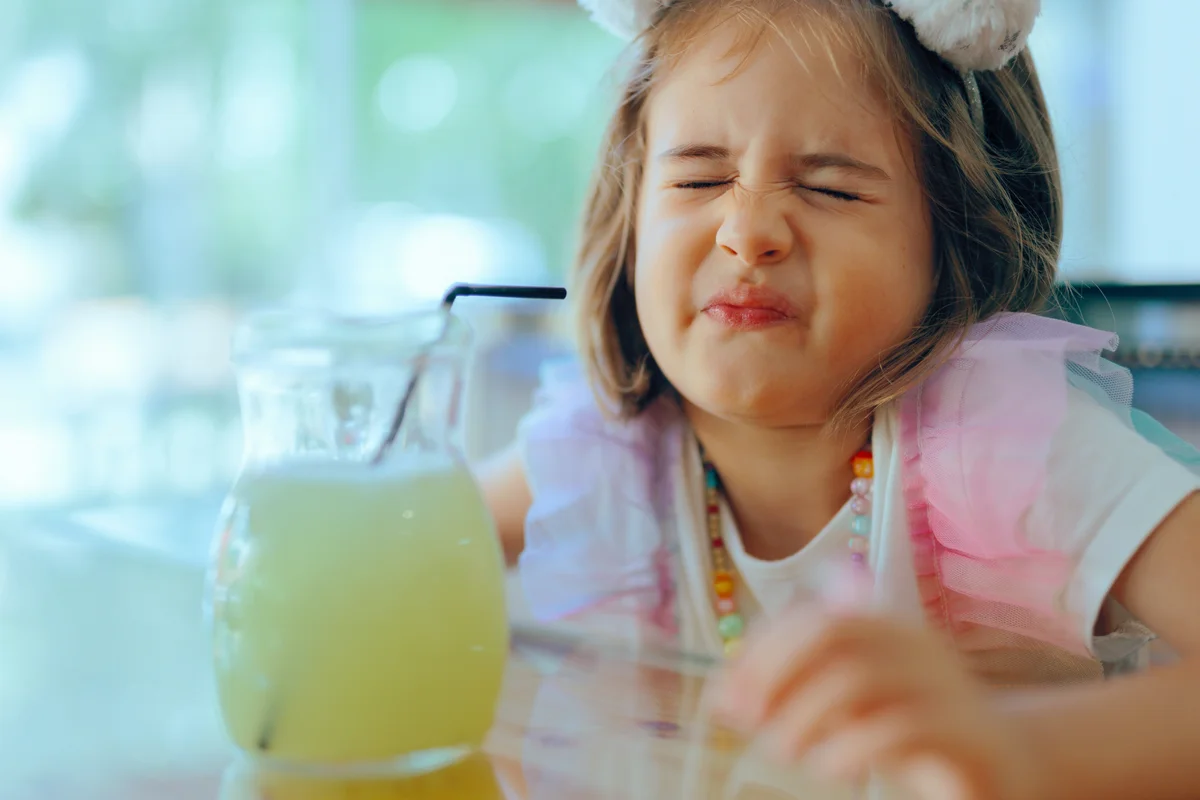 Girl Tasting Sour Lemonade making a Funny Grimace