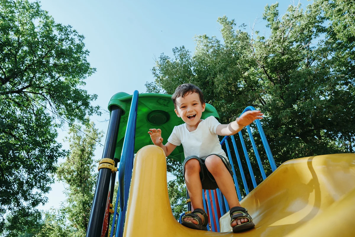 happy preschooler boy playing on a slide