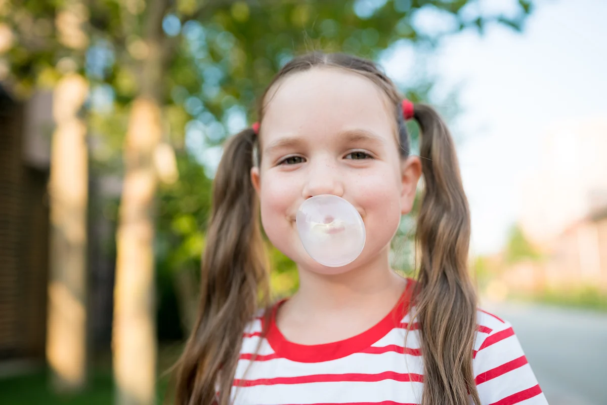 Portrait of smiling girl inflating bubble with chewing gum