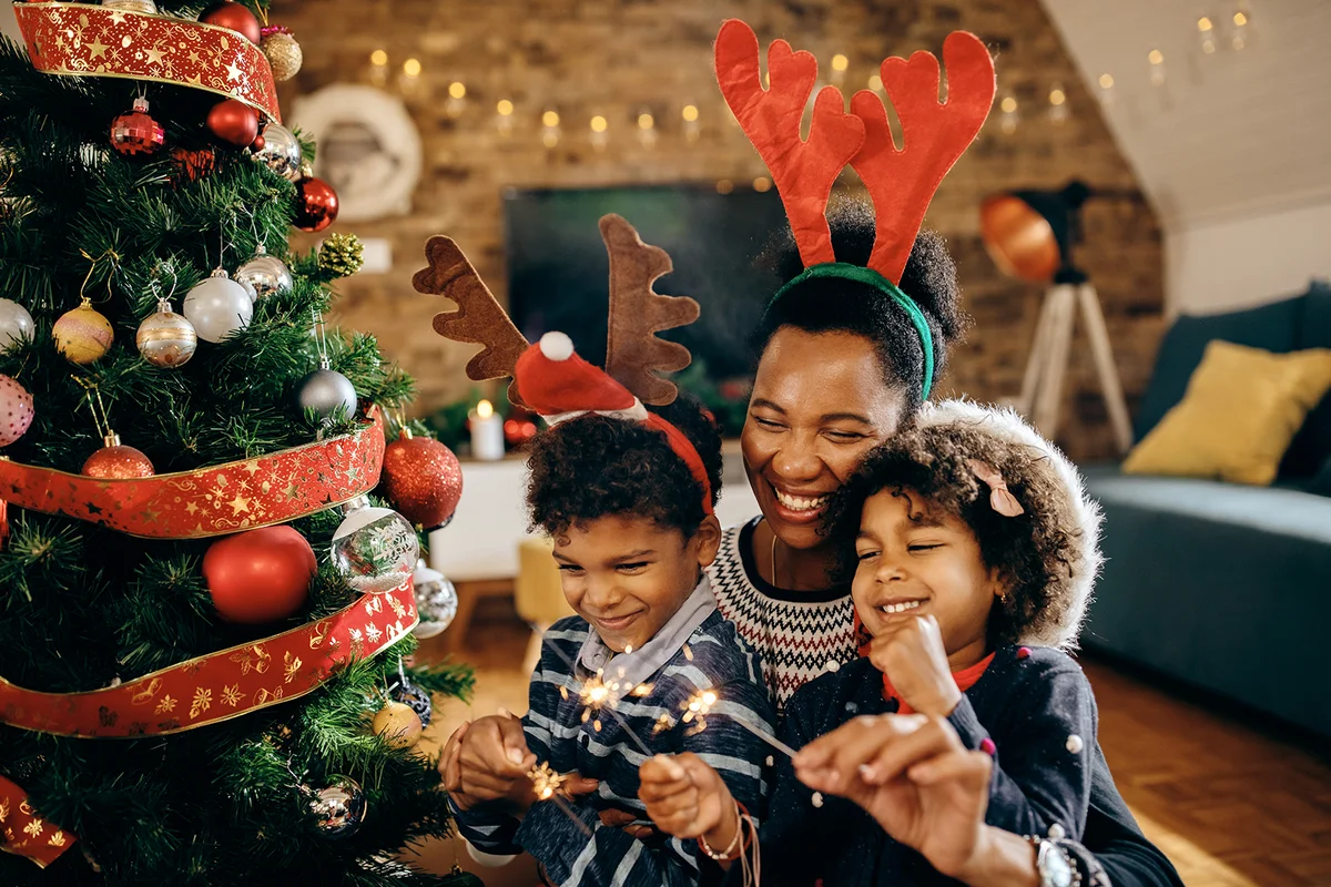 children having fun with their mother while using sparklers on Christmas at home