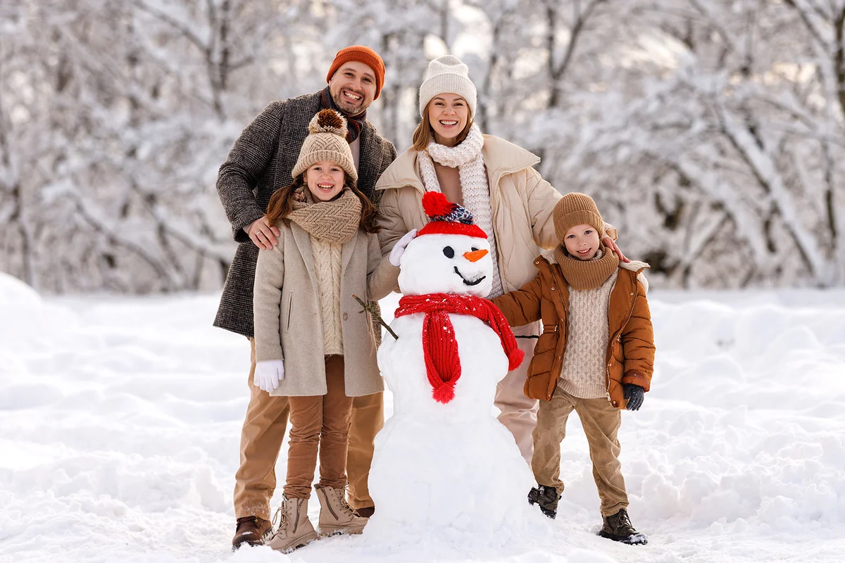 Happy family members laughing merrily while posing around cheerful funny snowman
