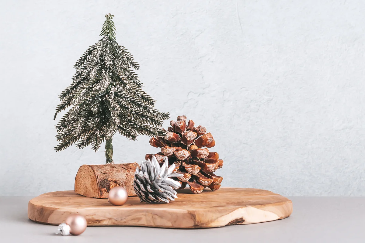 Christmas tree miniature, candle and pine cone on wooden board