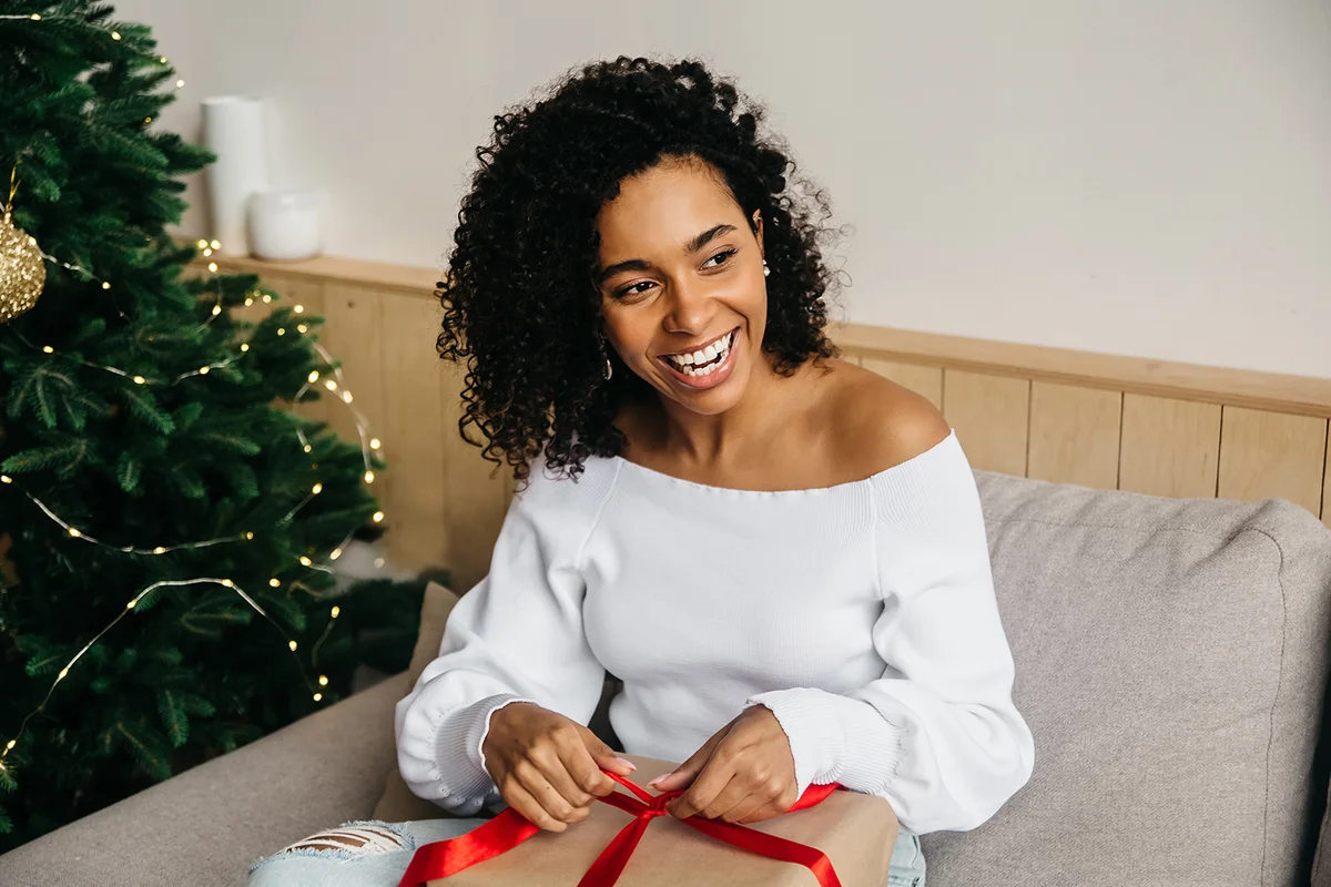 Happy laughing young woman opens box with christmas gift