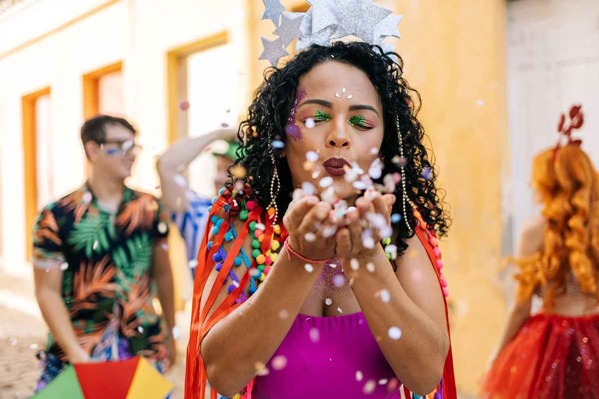 woman enjoying the carnival party blowing confetti