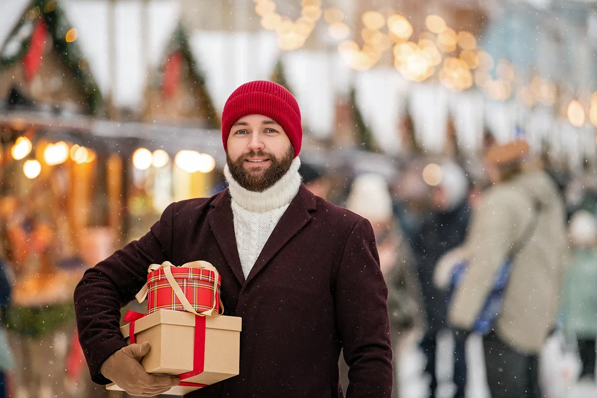 Happy smiling man in winter clothes at street Christmas market
