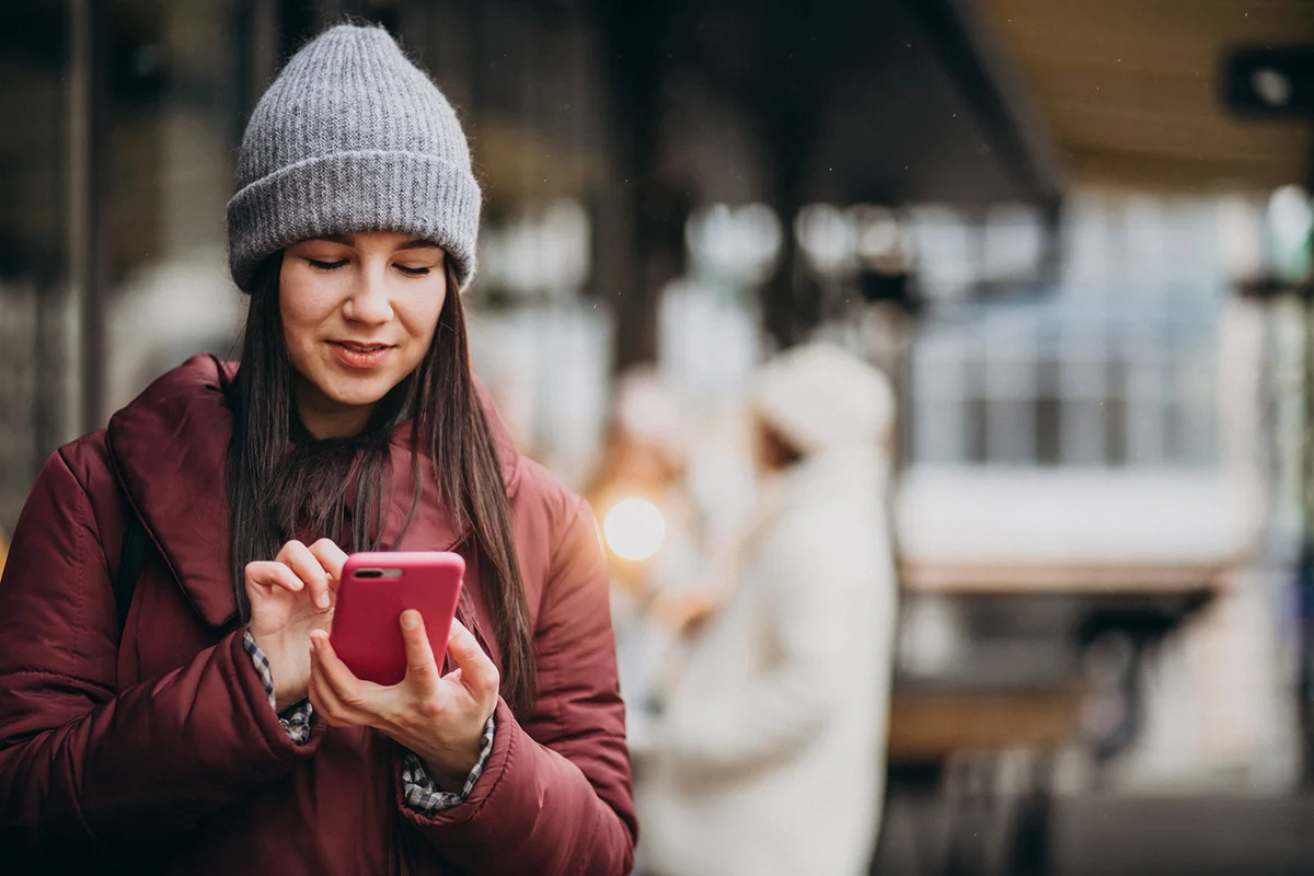 woman using phone outside the street and meeting with friends