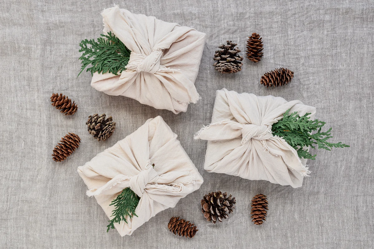 Group of three linen wrapped christmas presents with pinecones