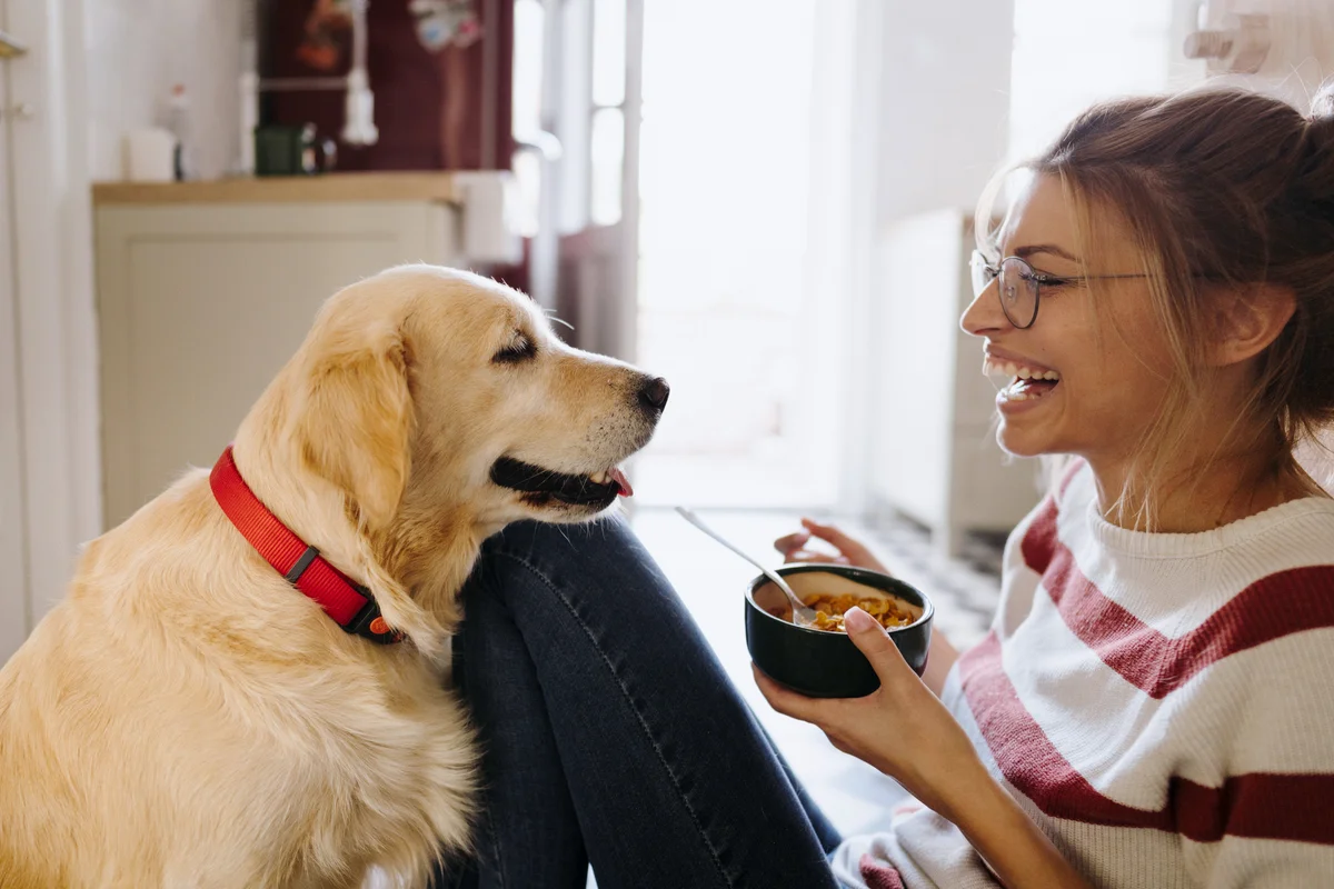 Young woman and her dog in a kitchen in the morning