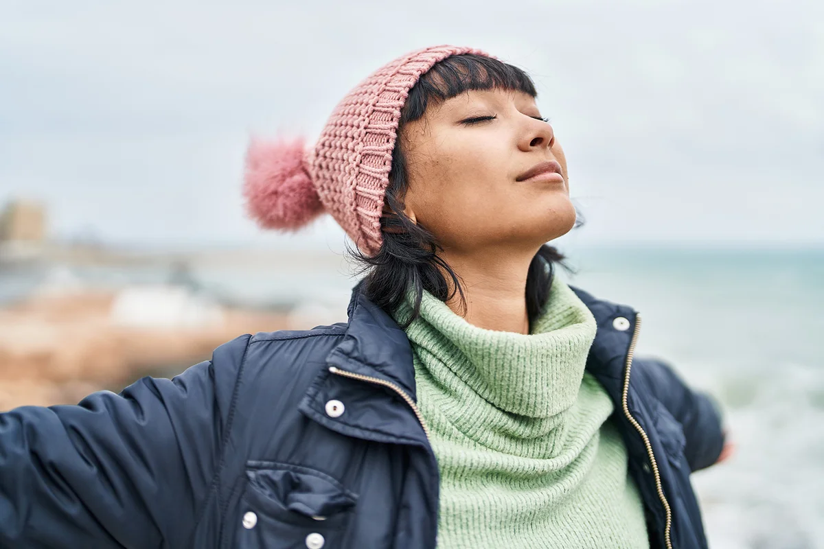 woman breathing with arms open at seaside