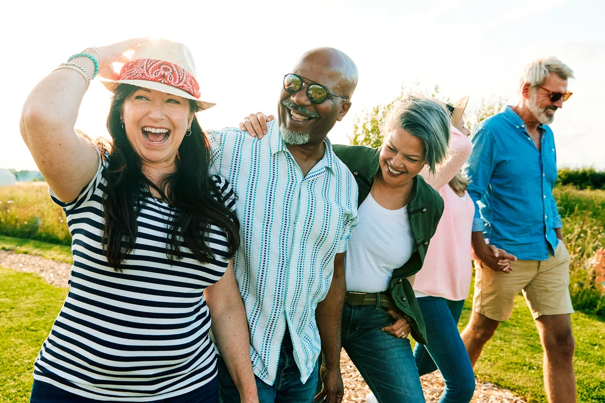 Group Of Mature Friends On Vacation Walking Along Path Through Campsite At Sunset