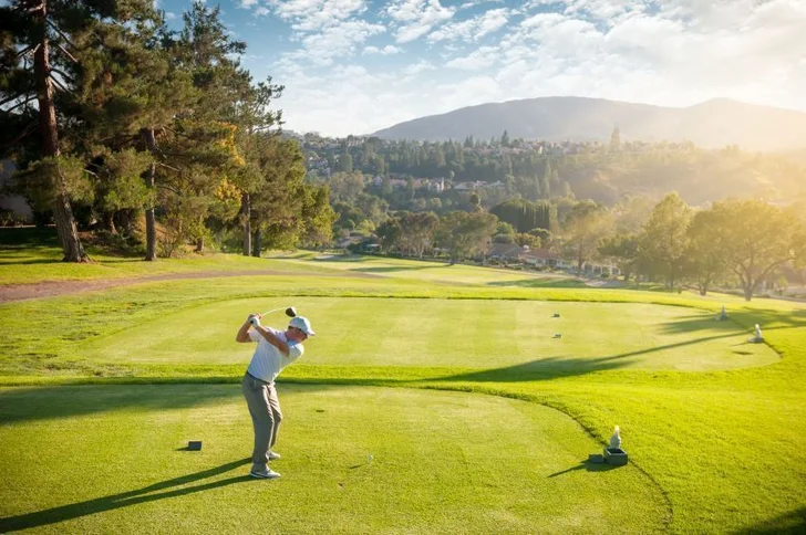 golfer tees off on dogleg left