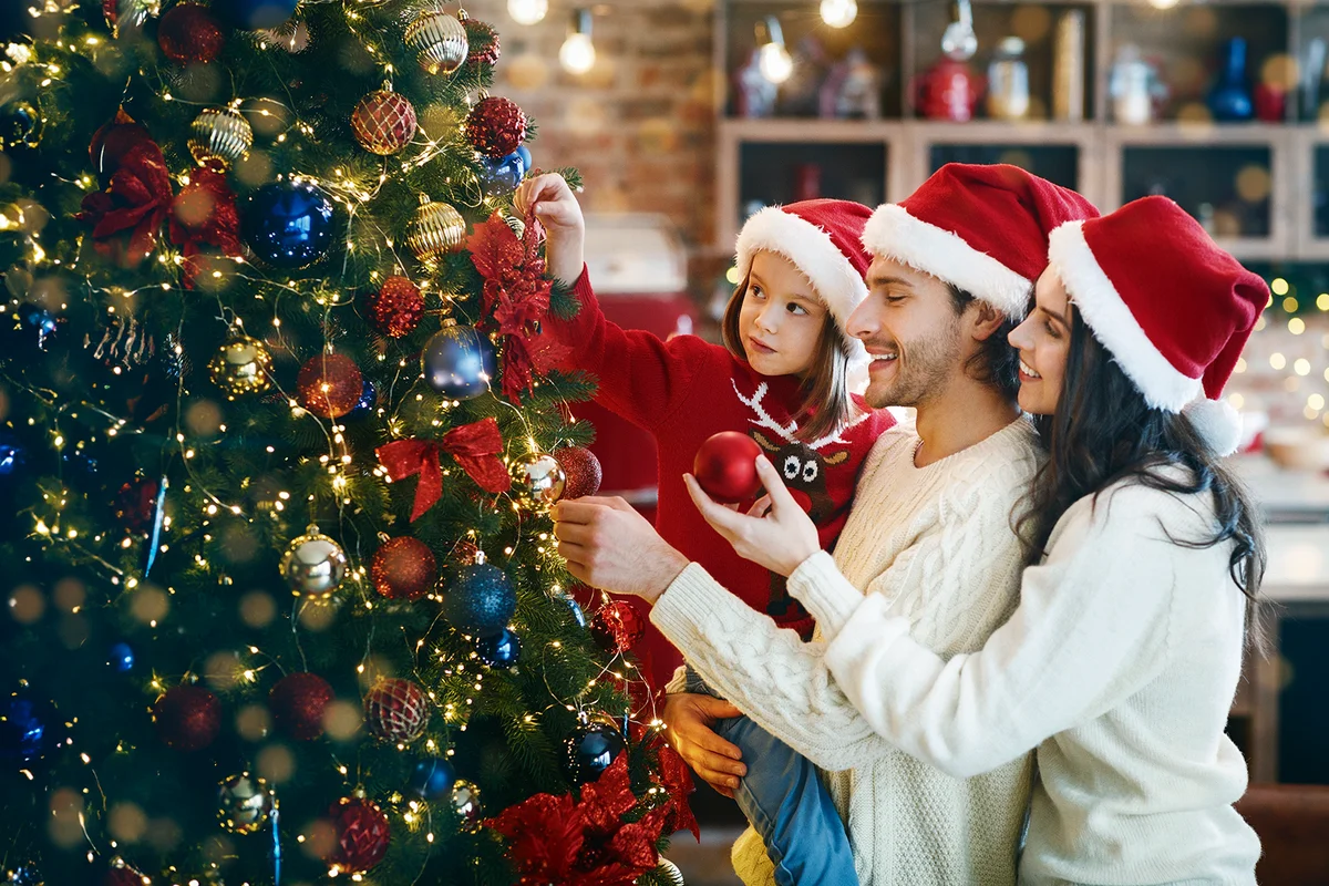 young family making Xmas tree together at home, getting ready before Christmas Eve,