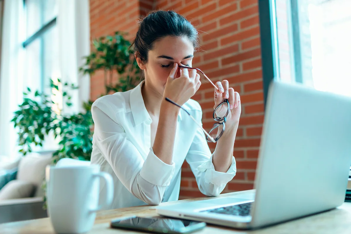 Shot of tired business woman with headache looking uncomfortable while working with computer in the office