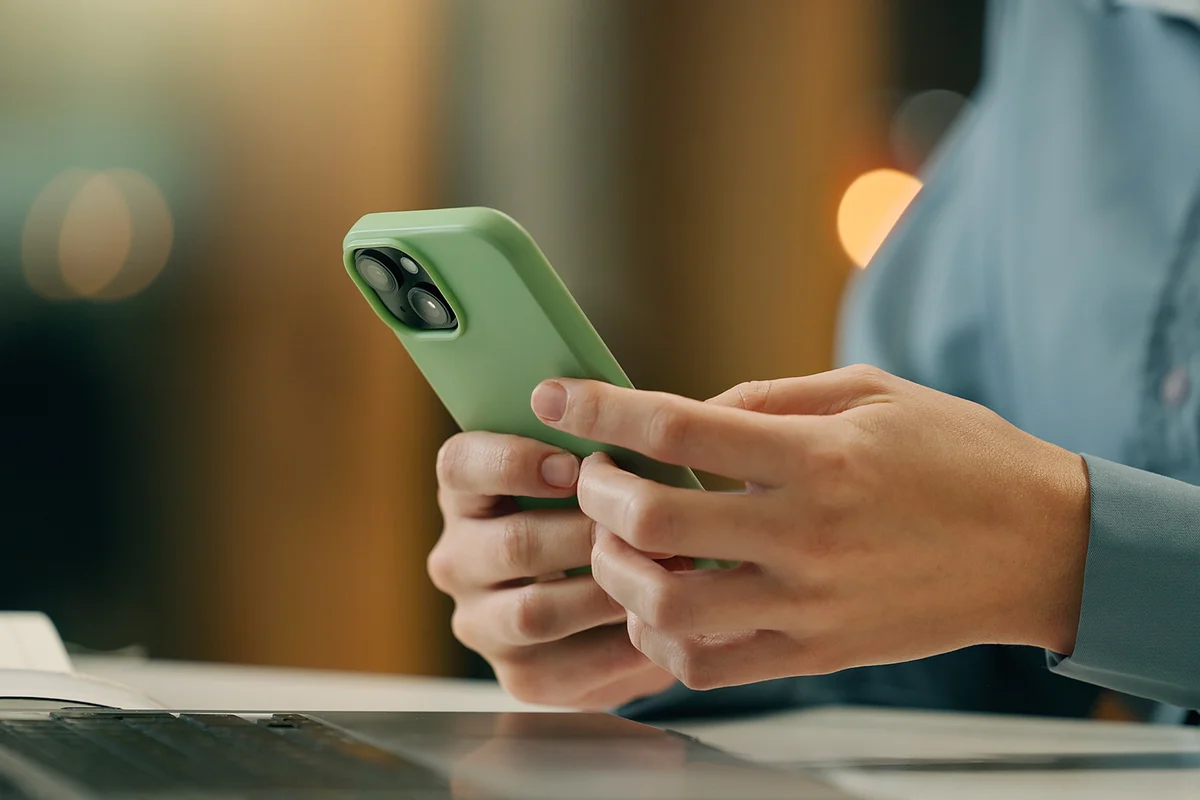 Business, person or hands with phone texting email in office for networking on app for social media. Closeup, laptop and secretary typing on mobile for research or online news on website at night