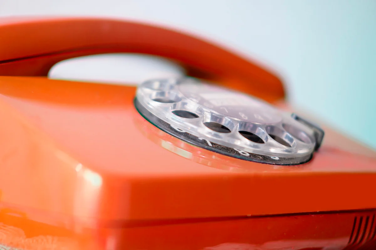 Old red Rotary Telephone with Disc Dial, Well-Maintained Antiques, calls helpline, Obsolete Technology, Retro Aesthetic 80s