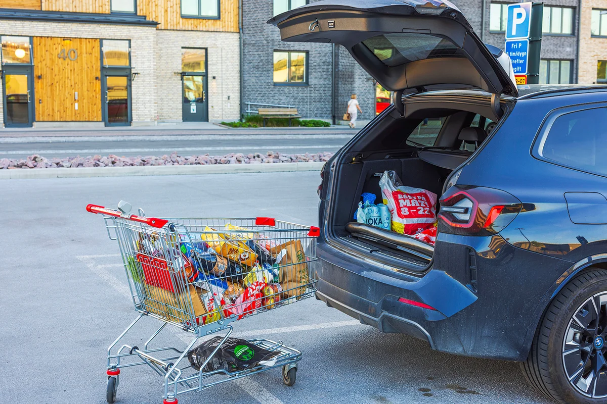 Close-up view of loading groceries from cart into open trunk