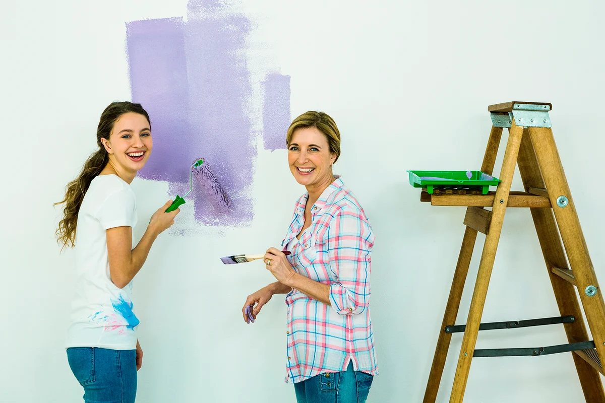 Mother and daughter painting a wall smiling