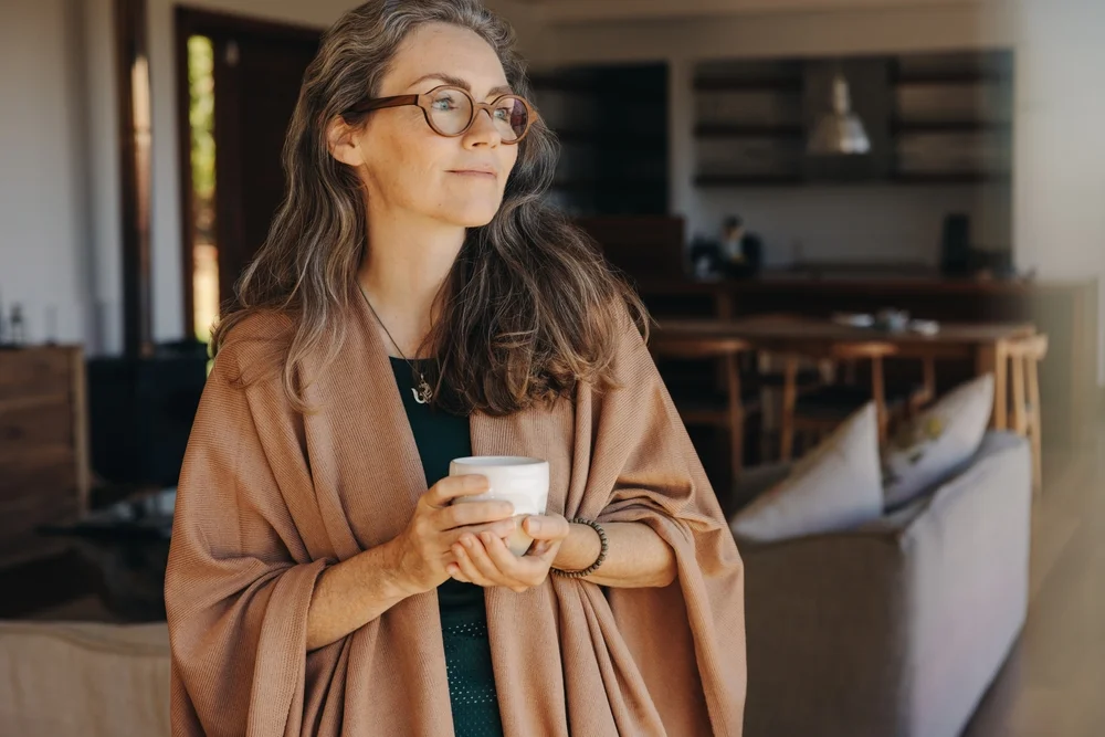 woman with cup of tea gazing out a window