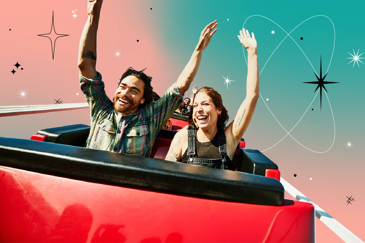 Laughing couple with arms raised riding roller coaster