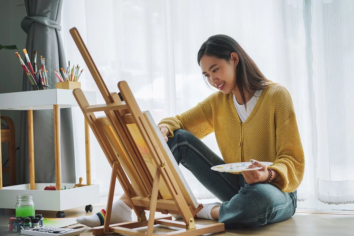 Female artist painting on canvas at home
