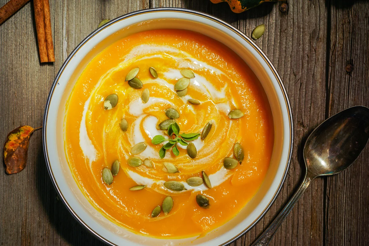 Vegetarian tasty spicy pumpkin soup bowl on a wooden background